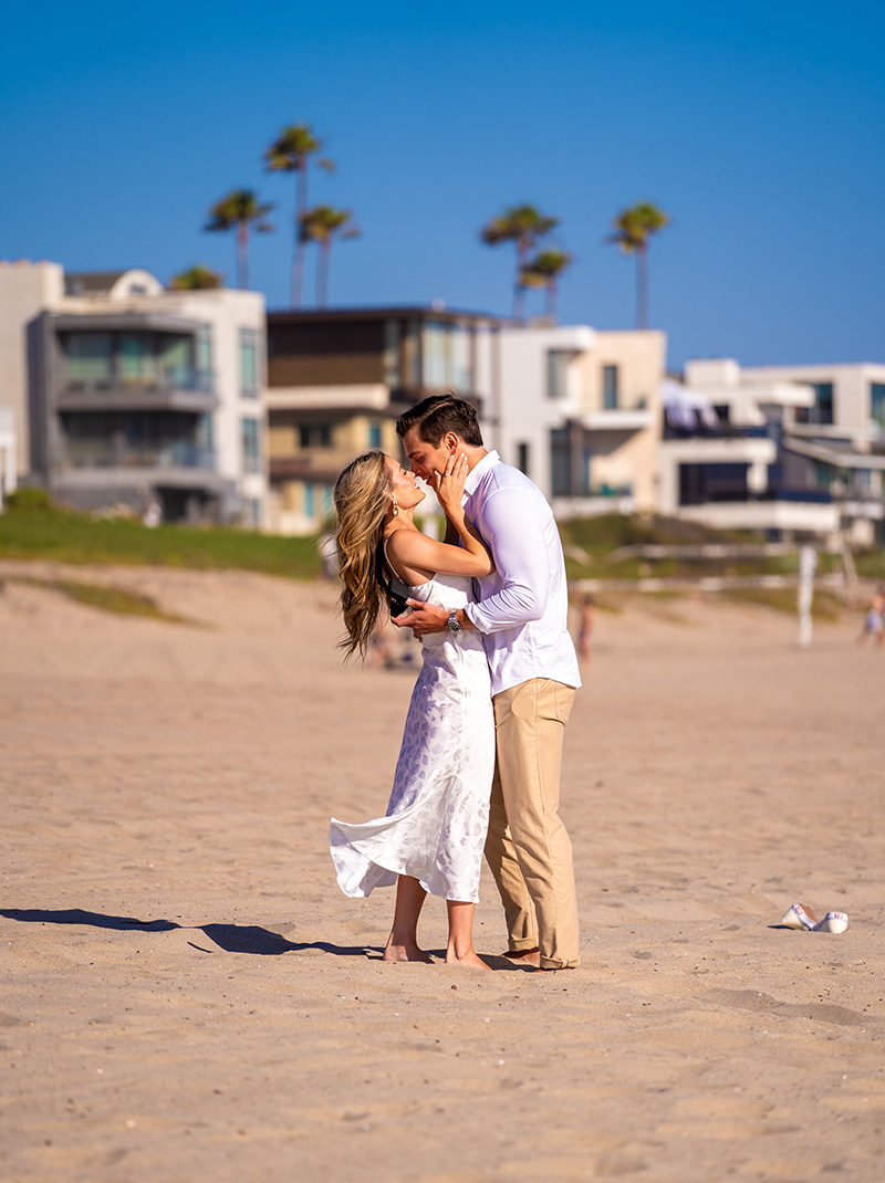 The couple embracing on the sand with beach houses behind