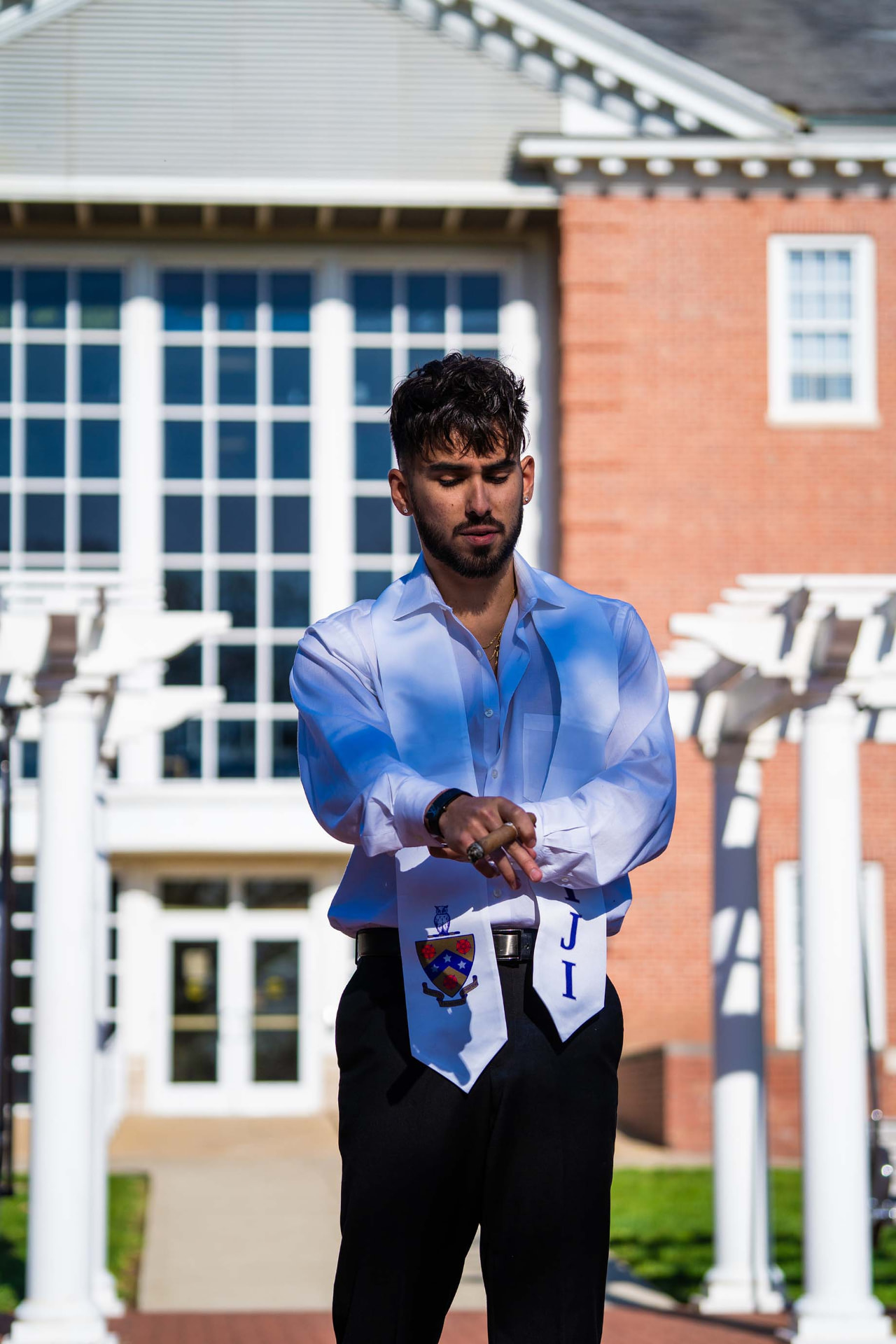 Graduate lighting a cigar outside a campus building