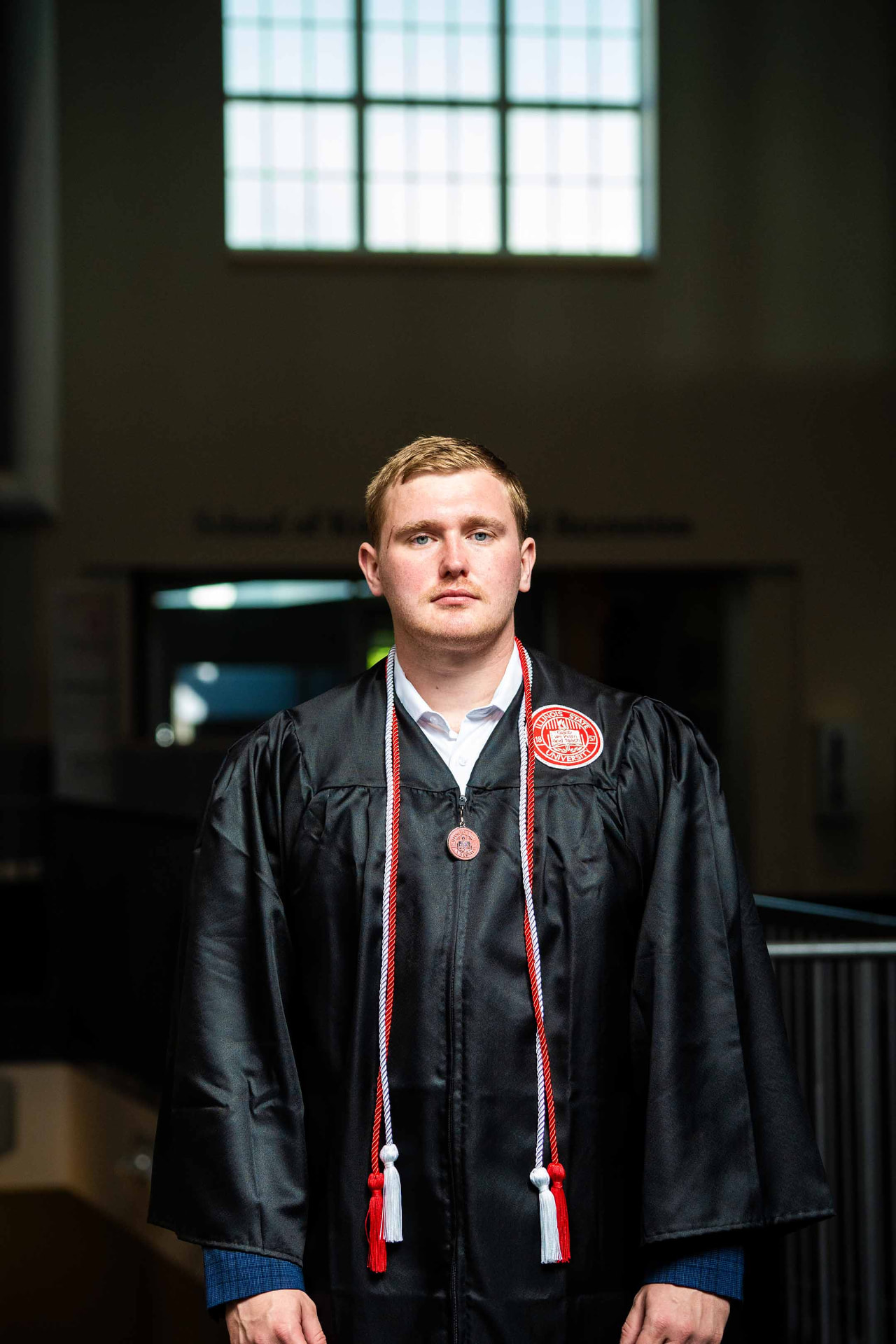 Portrait of a graduate with honor cords inside a campus building