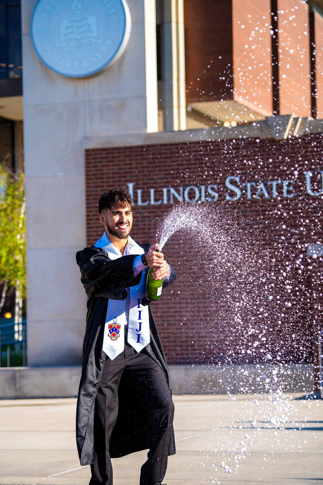 Graduate spraying champagne outside the campus library