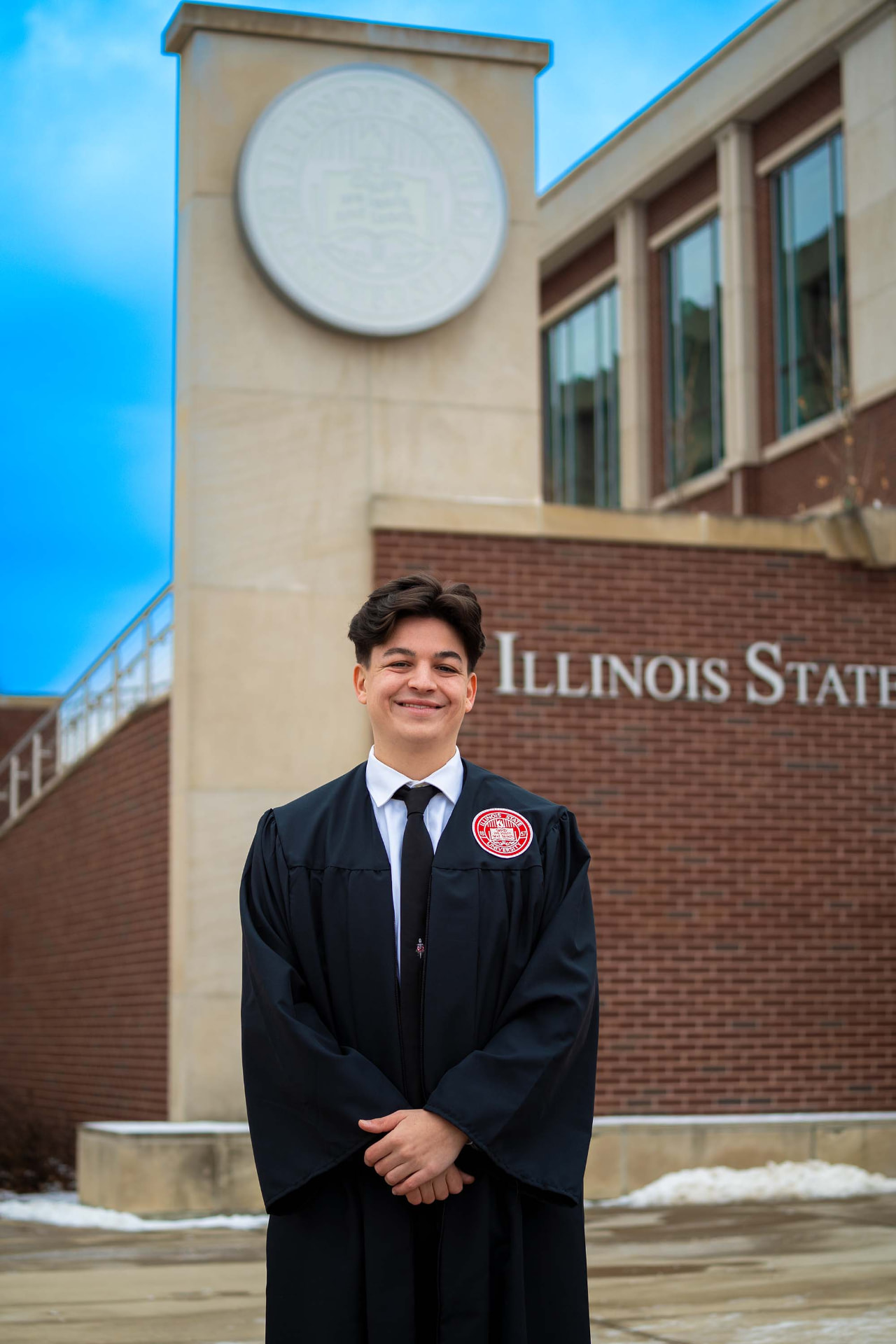 Graduate in front of the Illinois State University seal and sign