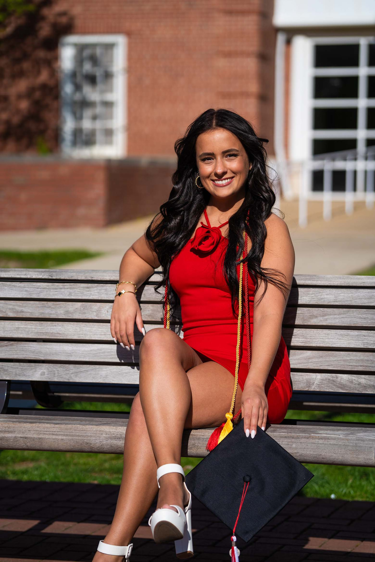 Graduate seated on a bench with her cap and cords